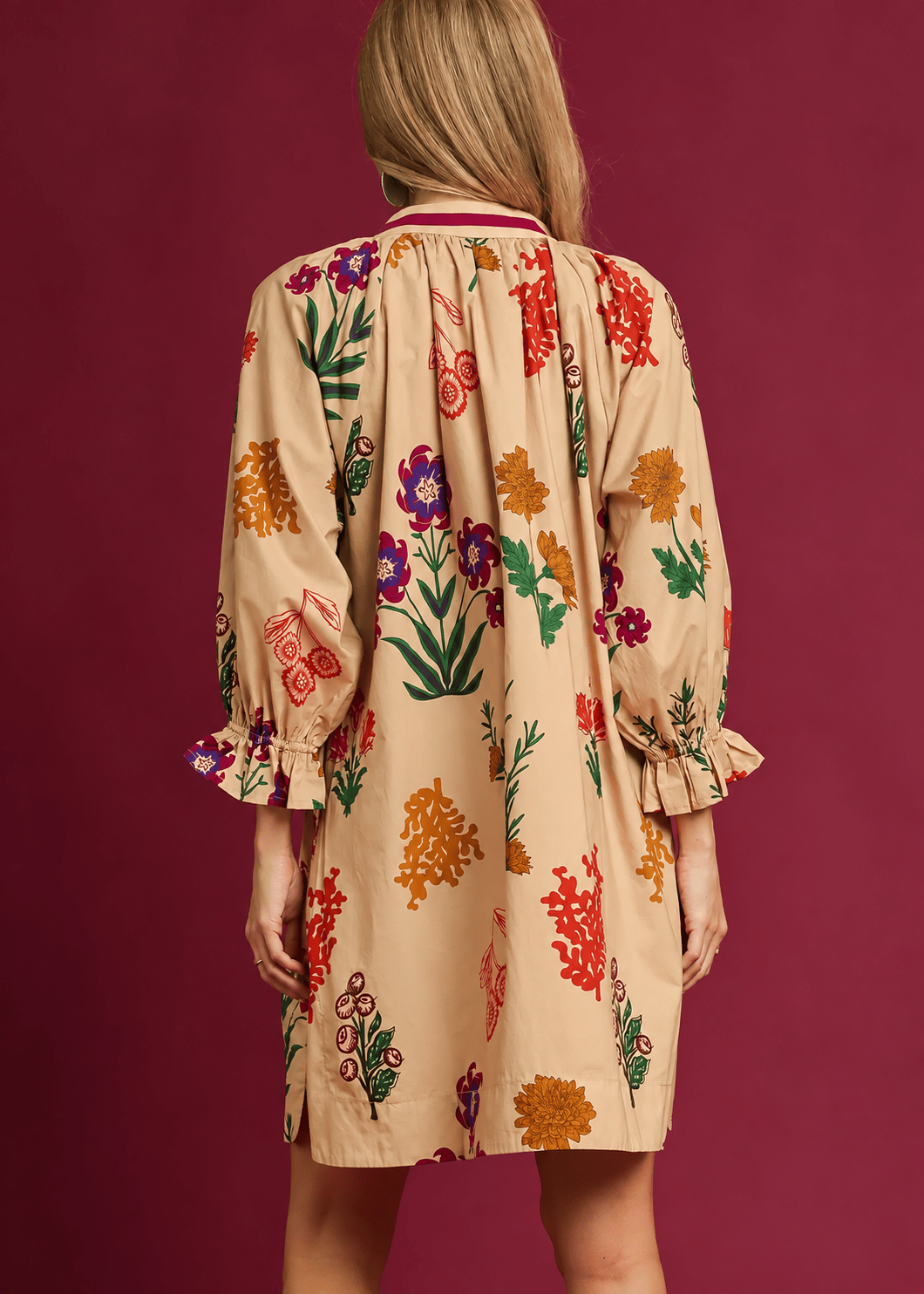 Back view of tan botanical floral shift dress with gathered neckline, relaxed silhouette, and ruffled sleeve cuffs.
