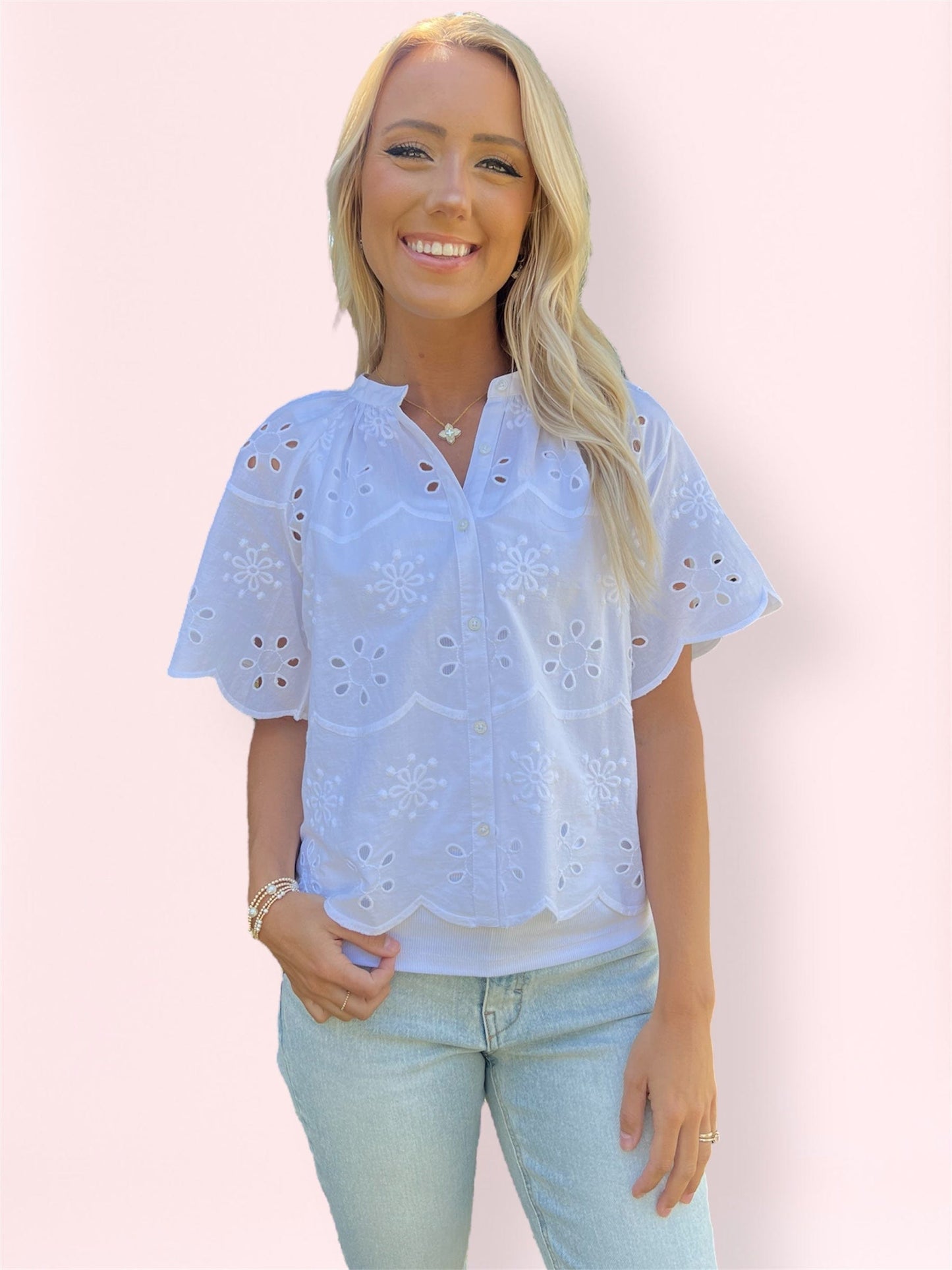Close-up detail of scalloped embroidery and eyelet floral pattern on white blouse