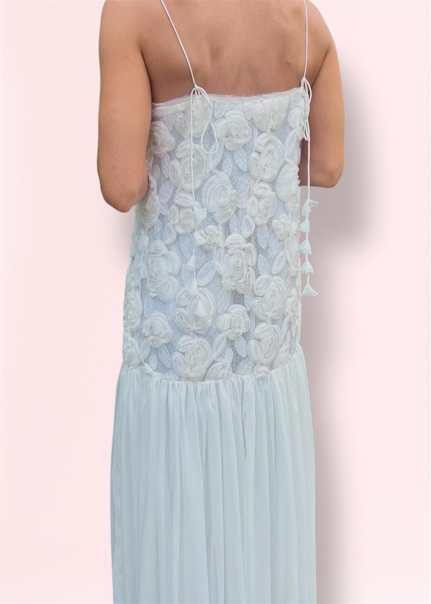 Back view of maxi dress showing adjustable spaghetti straps and textured floral lace design with sheer skirt.