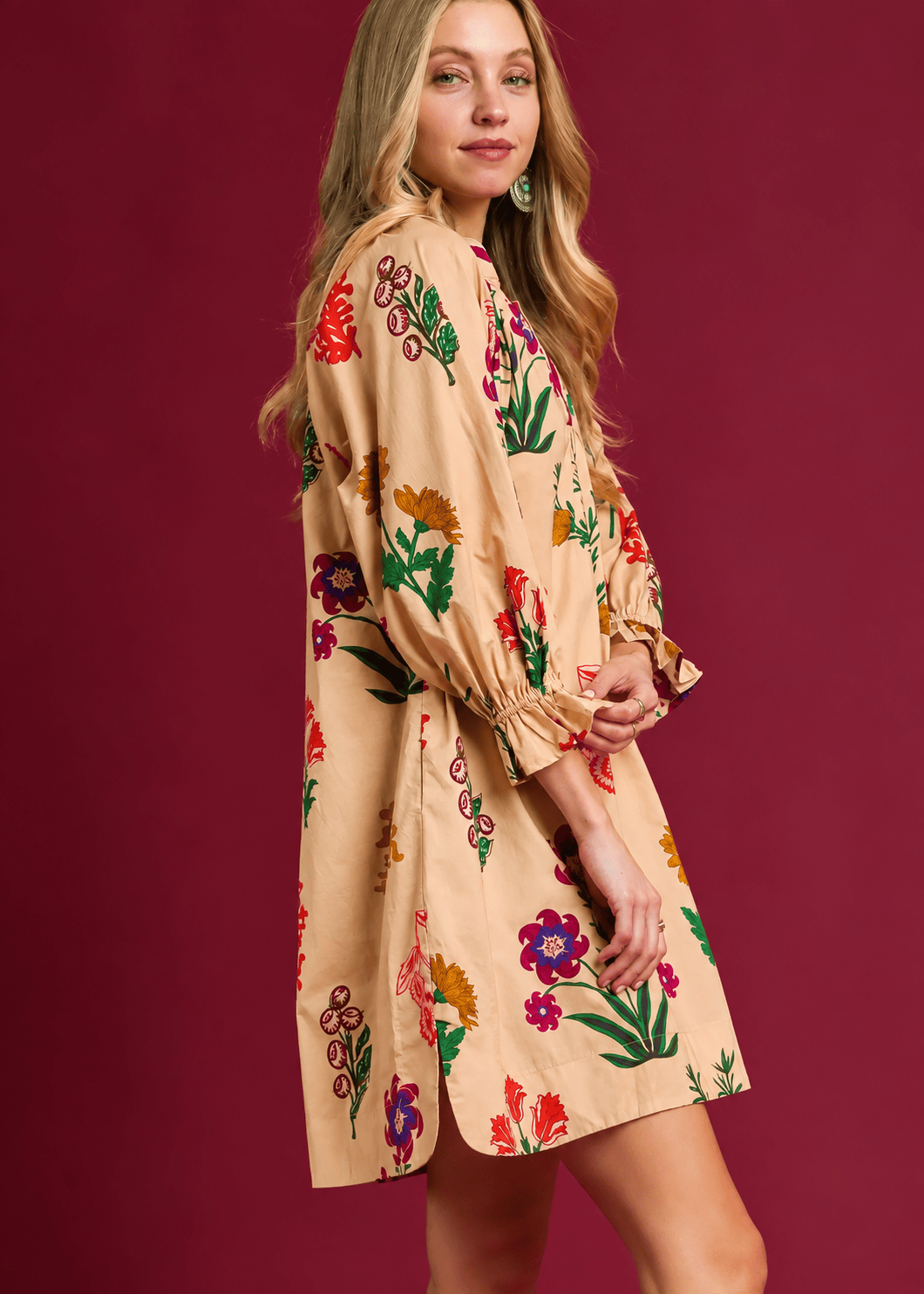 Side view of relaxed fit floral mini dress featuring three-quarter balloon sleeves, ruffle cuffs, and side hem slit.