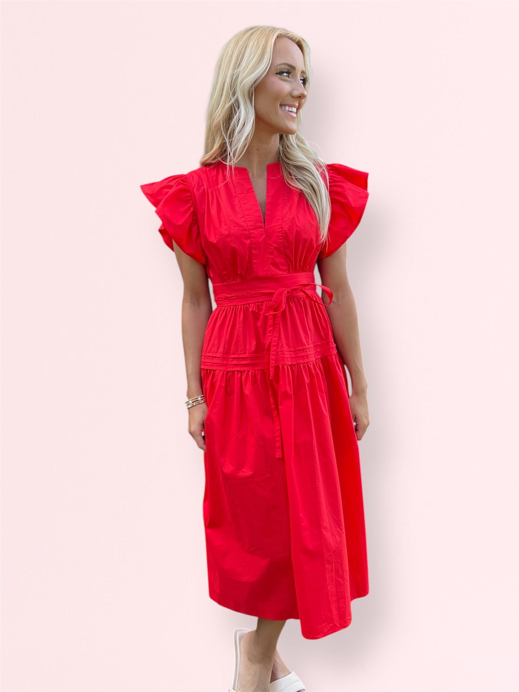 Front view of woman wearing the Cala Midi Dress with ruffle sleeves and a waist tie