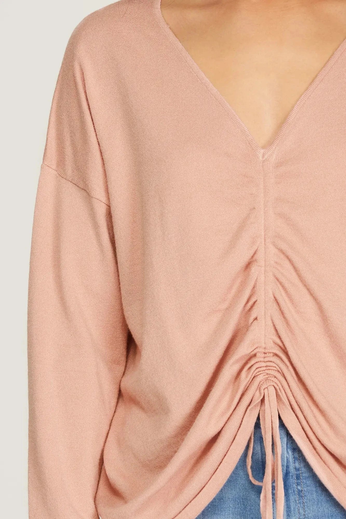 Close-up of drawstring ruching detail on soft blush knit sweater.