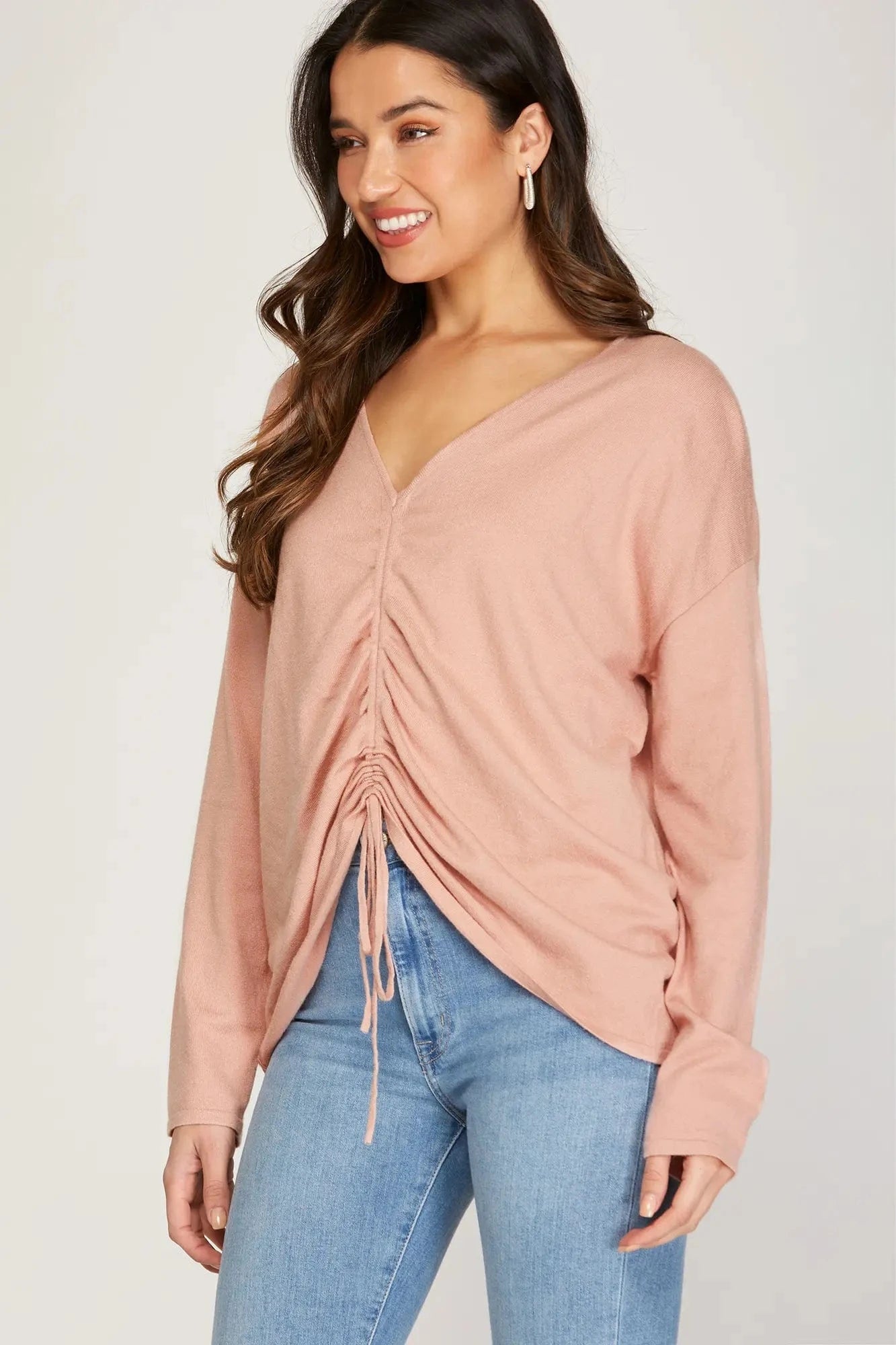 Side view of model in adjustable front ruched pink sweater.