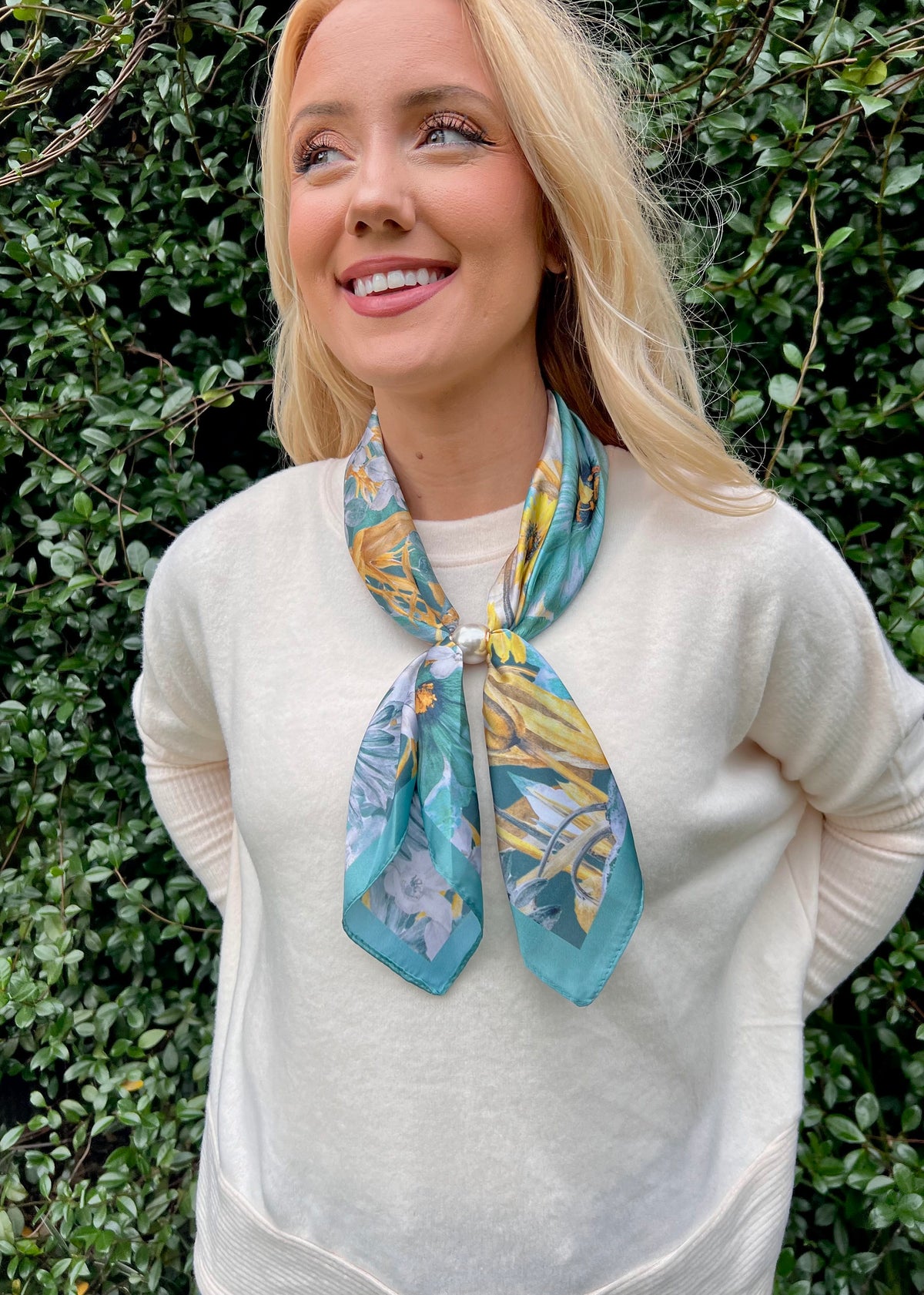 Woman wearing Golden Garden teal and gold floral magnetic scarf with cream sweater