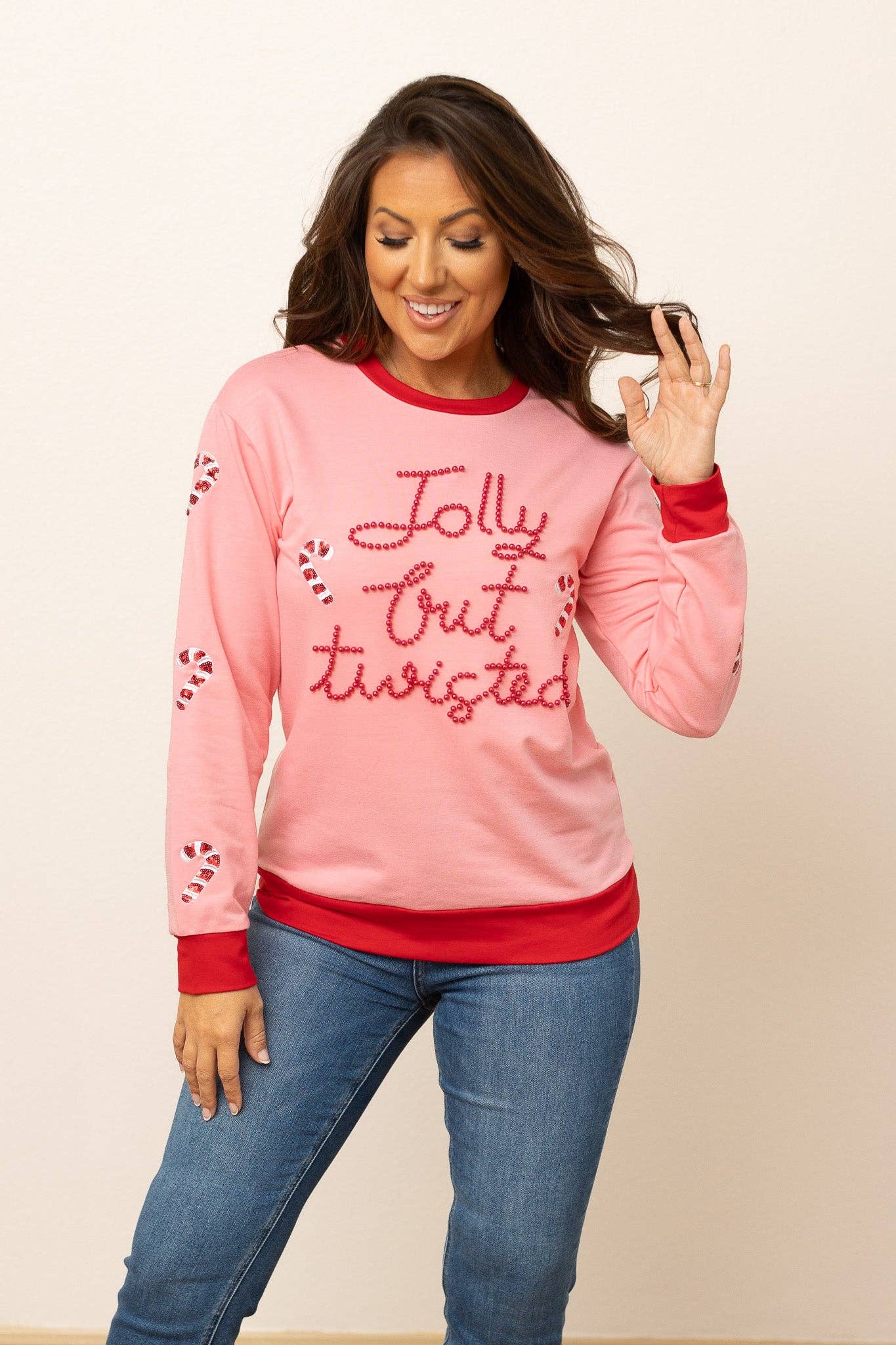 Pink Jolly but Twisted Christmas sweater with candy canes on sleeves and bold red cuffs