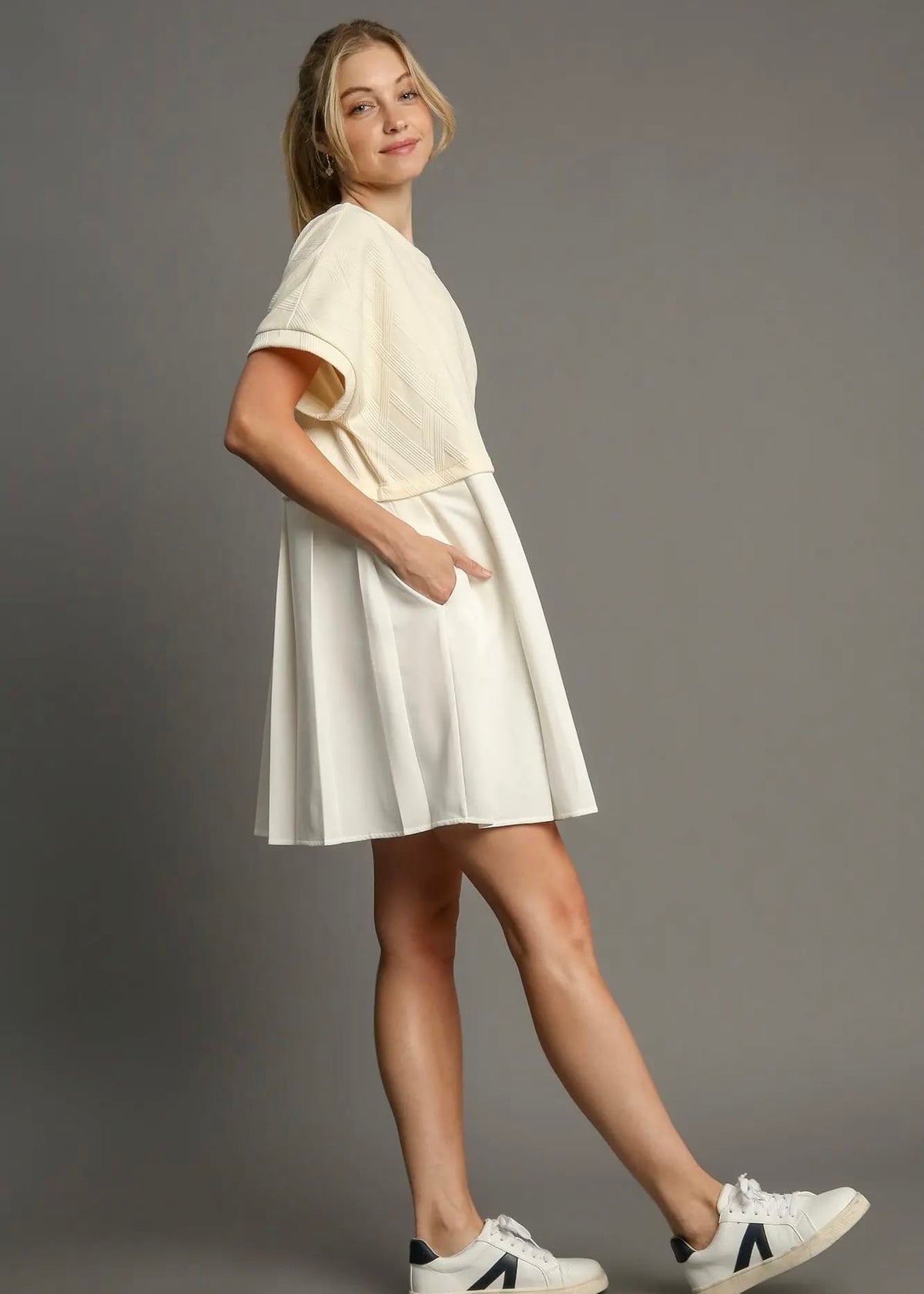Side view of ivory relaxed-fit mini dress styled with sneakers