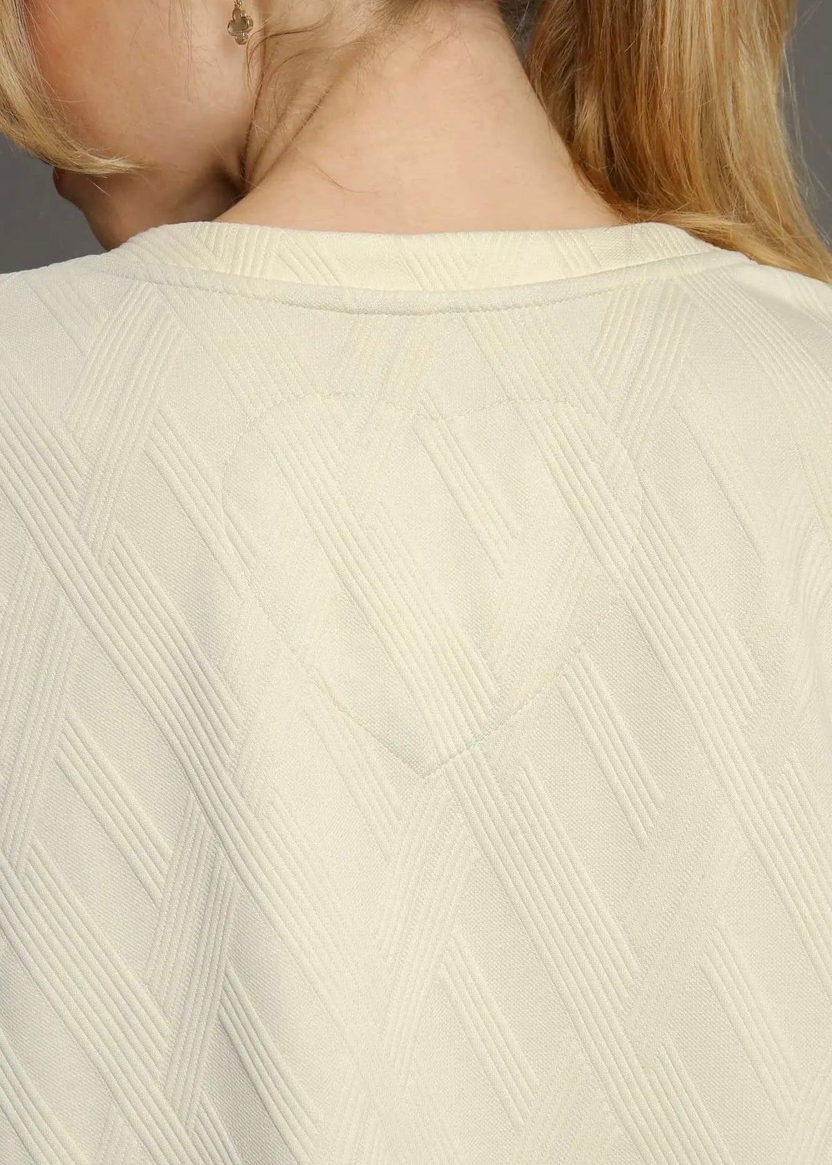 Close-up of geometric textured knit fabric on ivory dress
