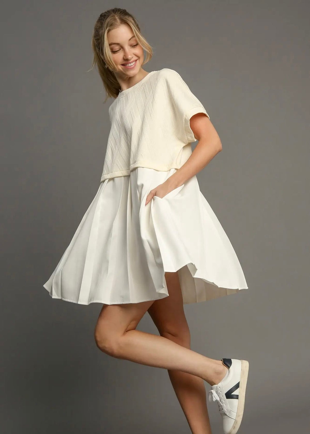 Woman wearing an ivory textured mini dress with white sneakers