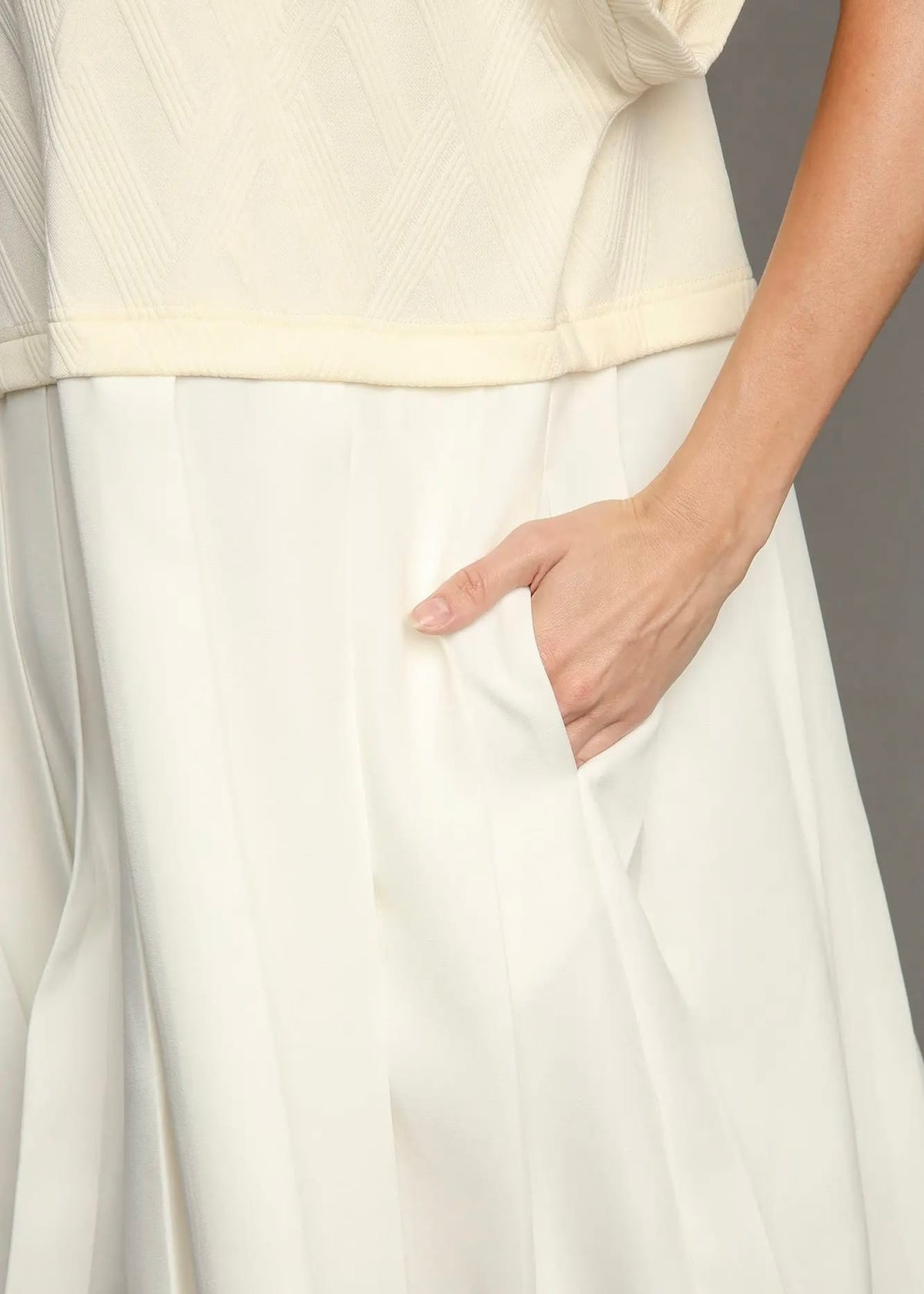 Close-up of side pocket and flowy skirt on ivory mini dress