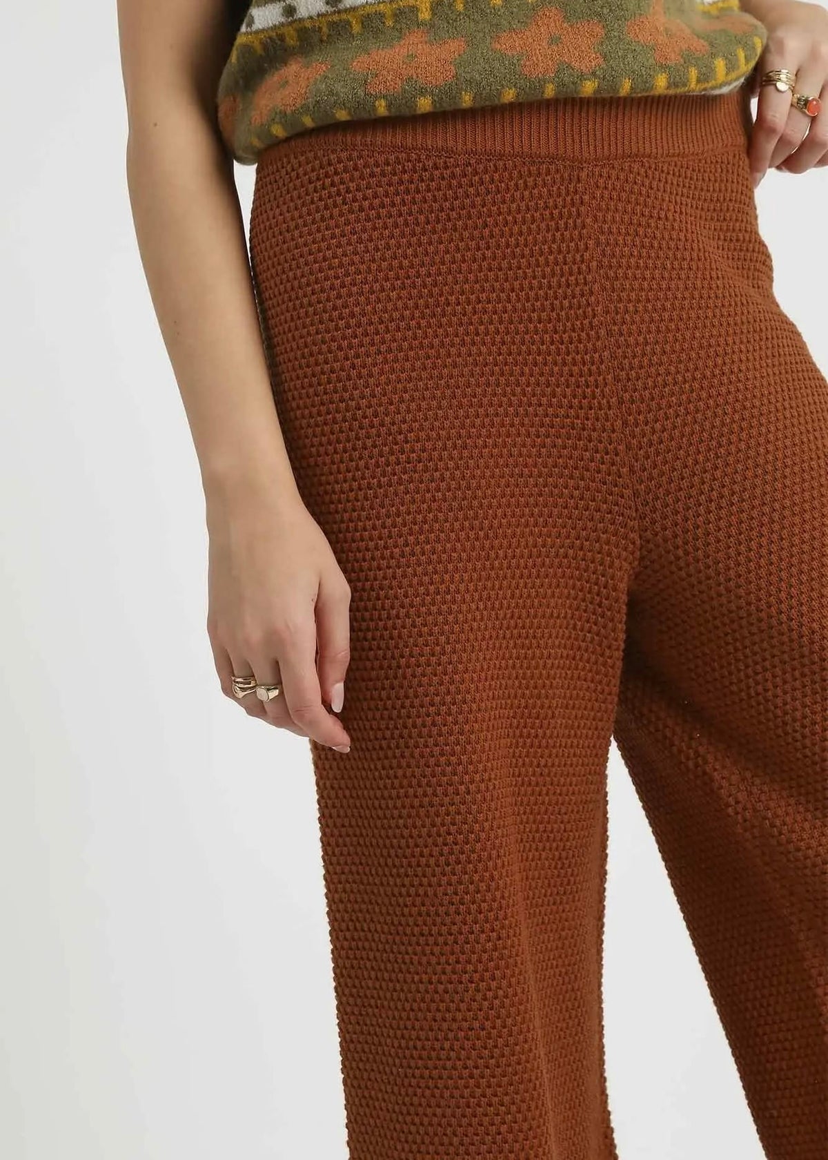 Close-up of rust colored textured knit pants and ribbed waistband